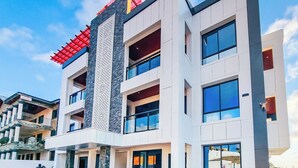 Un edificio moderno de varios pisos con techo plano, ventanas amplias y un panel vertical decorativo.