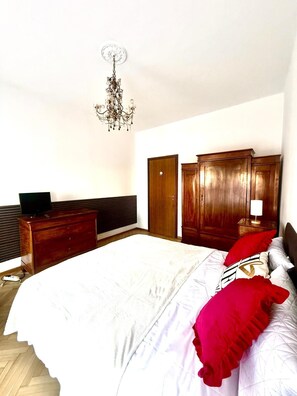 Un dormitorio con una cama grande, un armario de madera y un televisor sobre un aparador.