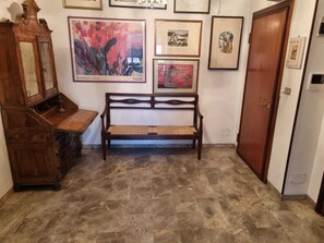 Un pasillo con un banco de madera, un armario de madera y obras enmarcadas en las paredes.