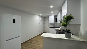 Una cocina moderna con armarios blancos, horno integrado y suelo de madera.