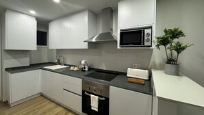 Una cocina moderna con armarios blancos, encimera negra, microondas, tostadora y una planta en maceta.
