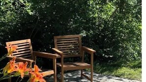 A stone patio with two wooden chairs and orange flowers. - Coastal Private Guest Suite (Cohasset)