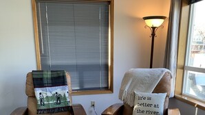 Dos sillones con mantas, una lámpara y una ventana con persianas.