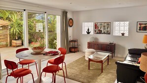 A modern living room with a dining area, large windows, and a view of the garden. - 3-room apartment, 2 bedrooms, terrace ;Bibi area (Biarritz)