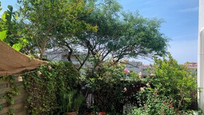 A wooden deck surrounded by lush greenery and flowering plants. - 3-room apartment, 2 bedrooms, terrace ;Bibi area (Biarritz)