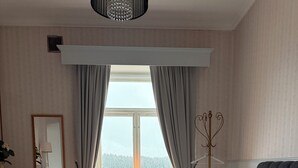 Une chambre à coucher avec un grand lit, une table de chevet, un miroir et une fenêtre avec des rideaux.