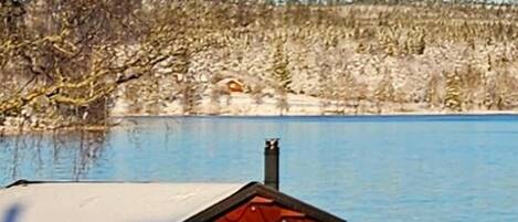 A cabin by a lake with a no swimming sign, a dock, and a snowy landscape.
