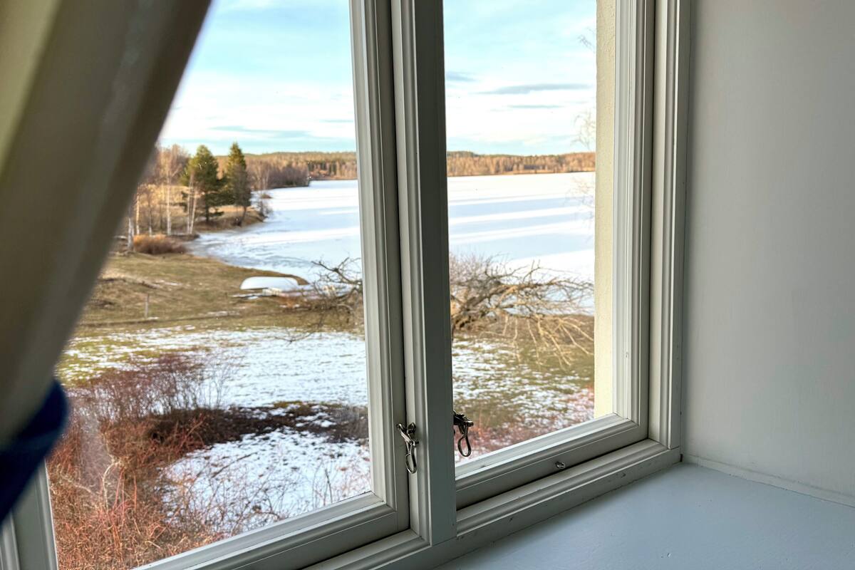 Una ventana con vistas a un río helado y árboles.