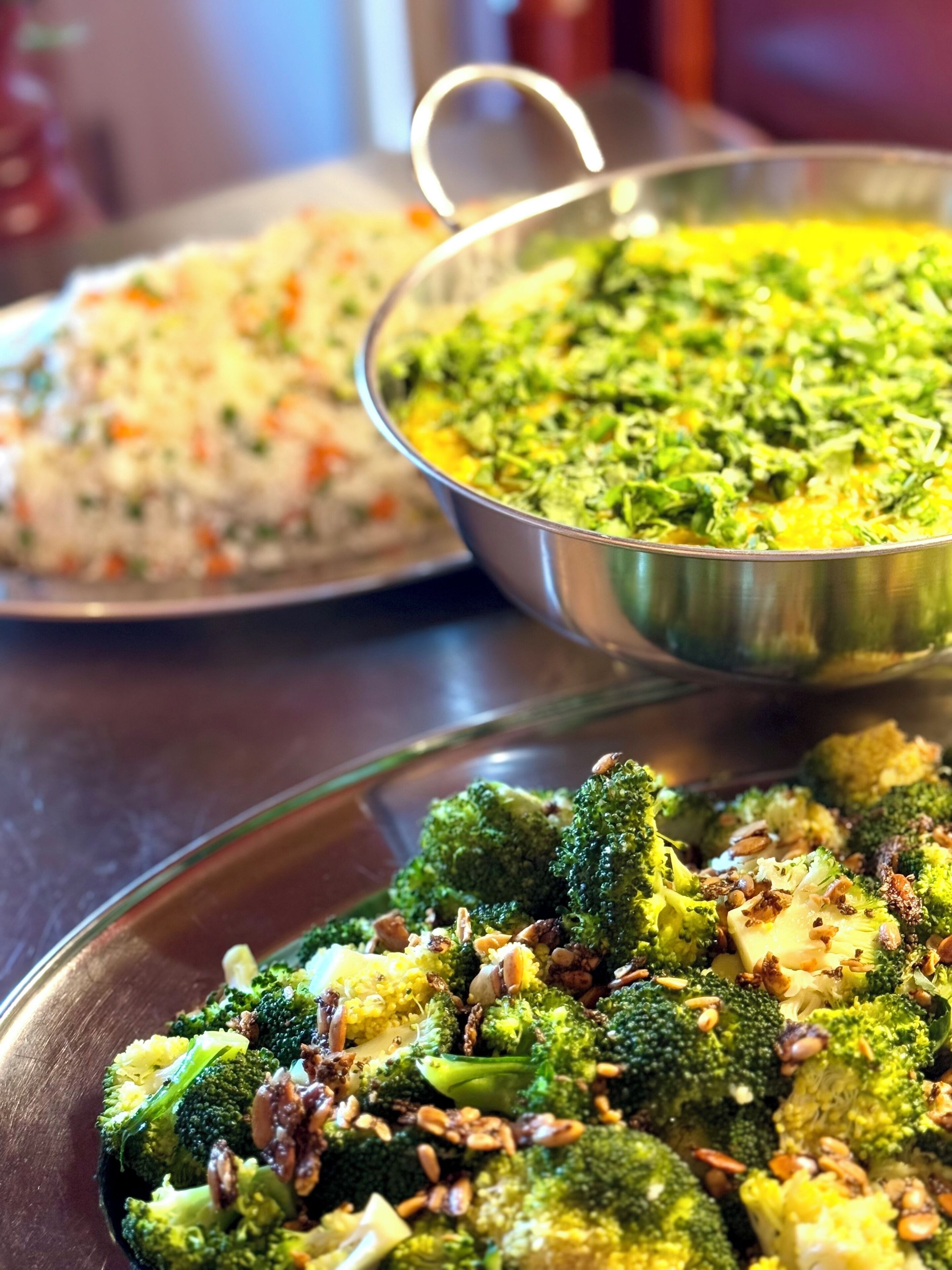 A close-up of a meal with broccoli and a bowl of green curry.