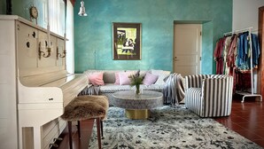Un salon aux murs de couleur turquoise, un canapé agrémenté de coussins à motifs, un fauteuil à rayures, une table basse et un fauteuil recouvert de fourrure.