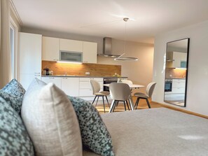 A modern kitchen with white cabinets, a wooden countertop, and a dining area with a table and chairs.