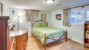 A bedroom with a wooden bed, a bedside table, a wardrobe, and a window with curtains.