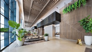 A modern lobby with large potted plants, a reception desk, and a high ceiling with wooden beams. - Skyline Chic Downtown Studio Getaway (Miami)