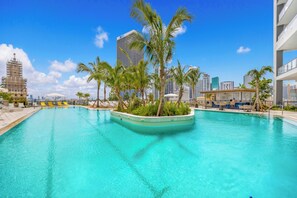 A swimming pool with palm trees, a sun lounger area, and a view of tall buildings. - Skyline Chic Downtown Studio Getaway (Miami)
