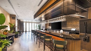 A modern bar area with a long counter, bar stools, and a brick wall backdrop. - Skyline Chic Downtown Studio Getaway (Miami)
