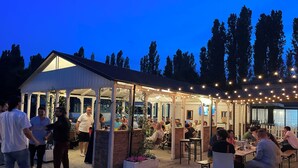 An outdoor patio area with tables and chairs, surrounded by a covered structure with string lights. - TENUTA SANTO STEFANO - HOTEL (Campagnola Emilia)