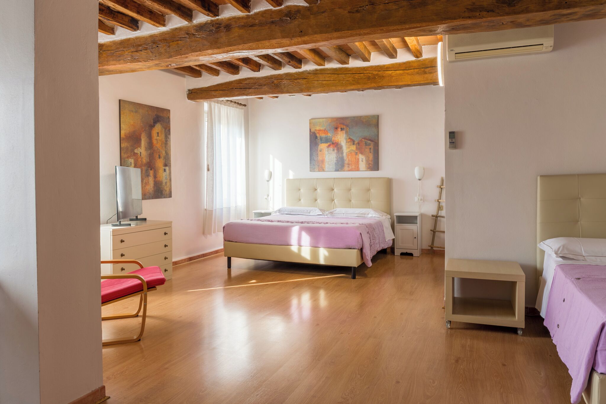 Una camera da letto con un letto, comodini, una cassettiera, una sedia e opere d'arte alle pareti.