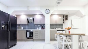 Una cocina moderna con electrodomésticos de acero inoxidable, microondas y un reloj en la pared.