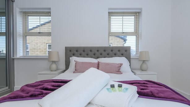 A neatly made bed with a grey headboard, two bedside lamps, and a purple blanket. - Corner by the Canal - Leeds Central Duplex - Pass the Keys (Leeds)