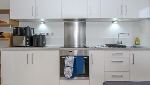 A modern kitchen with white cabinets, a stainless steel range hood, a built-in oven, and a microwave. - Corner by the Canal - Leeds Central Duplex - Pass the Keys (Leeds)