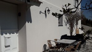 Eine Terrasse mit Steinböden, einem Tisch und Stühlen.