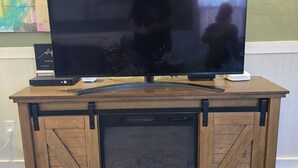 Ett möbelstycke i trä som används för underhållning, med en platt-TV, en ljudlimpa och en spelkonsol.