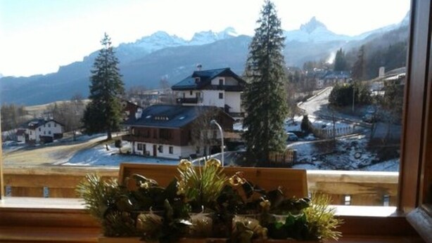 A view from a window overlooking a snowy landscape with houses and mountains. - Cozy apartment with beautiful view of the Olympic Cortina d' Ampezzo (Cortina d'Ampezzo)