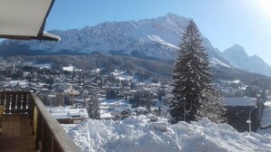 A snowy mountain landscape with a town below and a wooden balcony in the foreground. - Cozy apartment with beautiful view of the Olympic Cortina d' Ampezzo (Cortina d'Ampezzo)