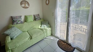 A green sofa with patterned cushions, a welcome sign, and a decorative wreath on the wall. - Charming holiday home 400m from the beach (Saint-Hilaire-de-Riez)