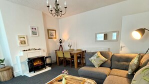 Una sala de estar con sofá, mesa de centro, chimenea y candelabro.