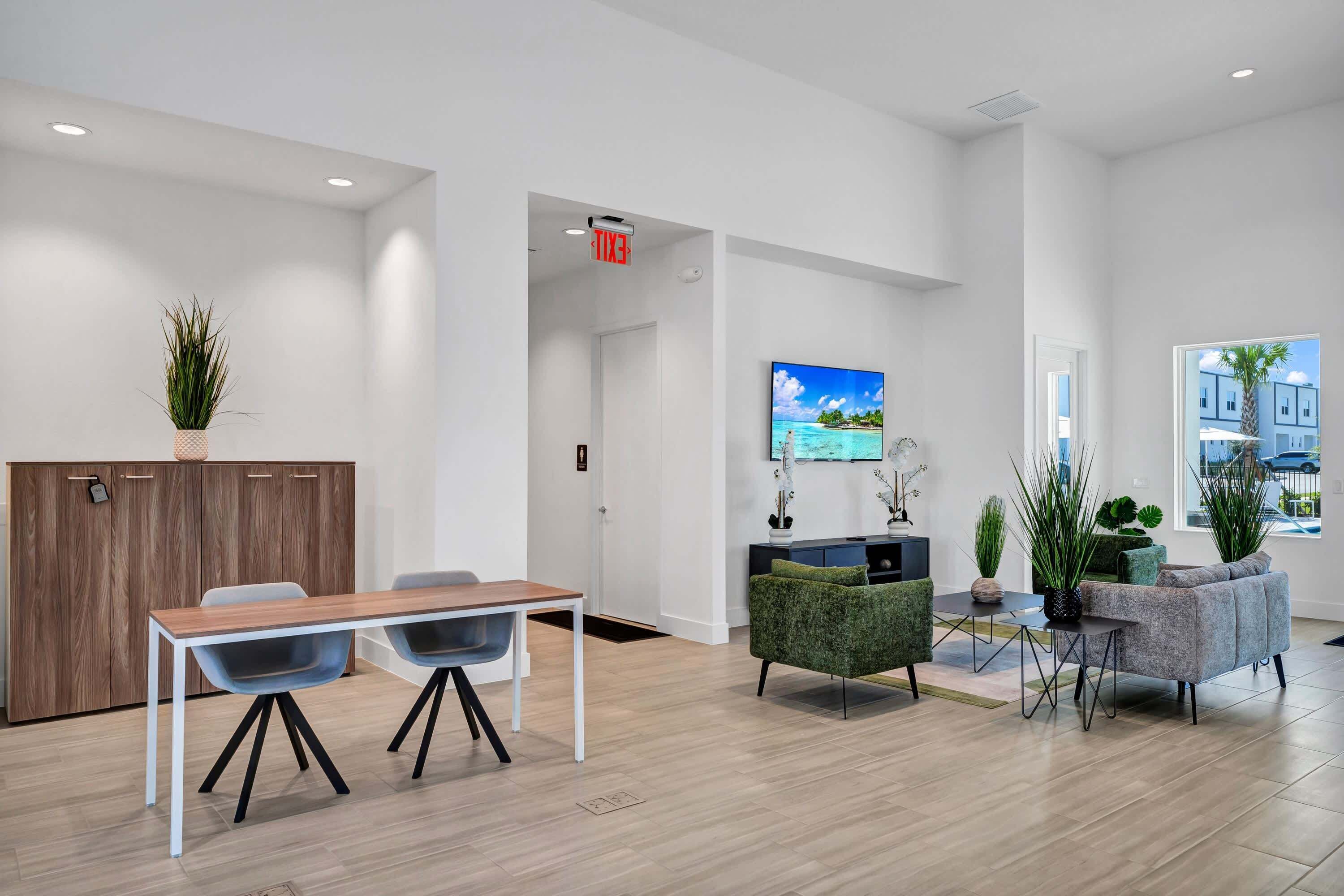 Eine moderne Hotellobby mit einer Rezeption, einem Essbereich, einer Couch und einem Fernsehbildschirm, der eine schöne Aussicht zeigt.