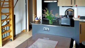 Una cocina moderna con armarios de madera, horno empotrado y un comedor con mesa para dos.