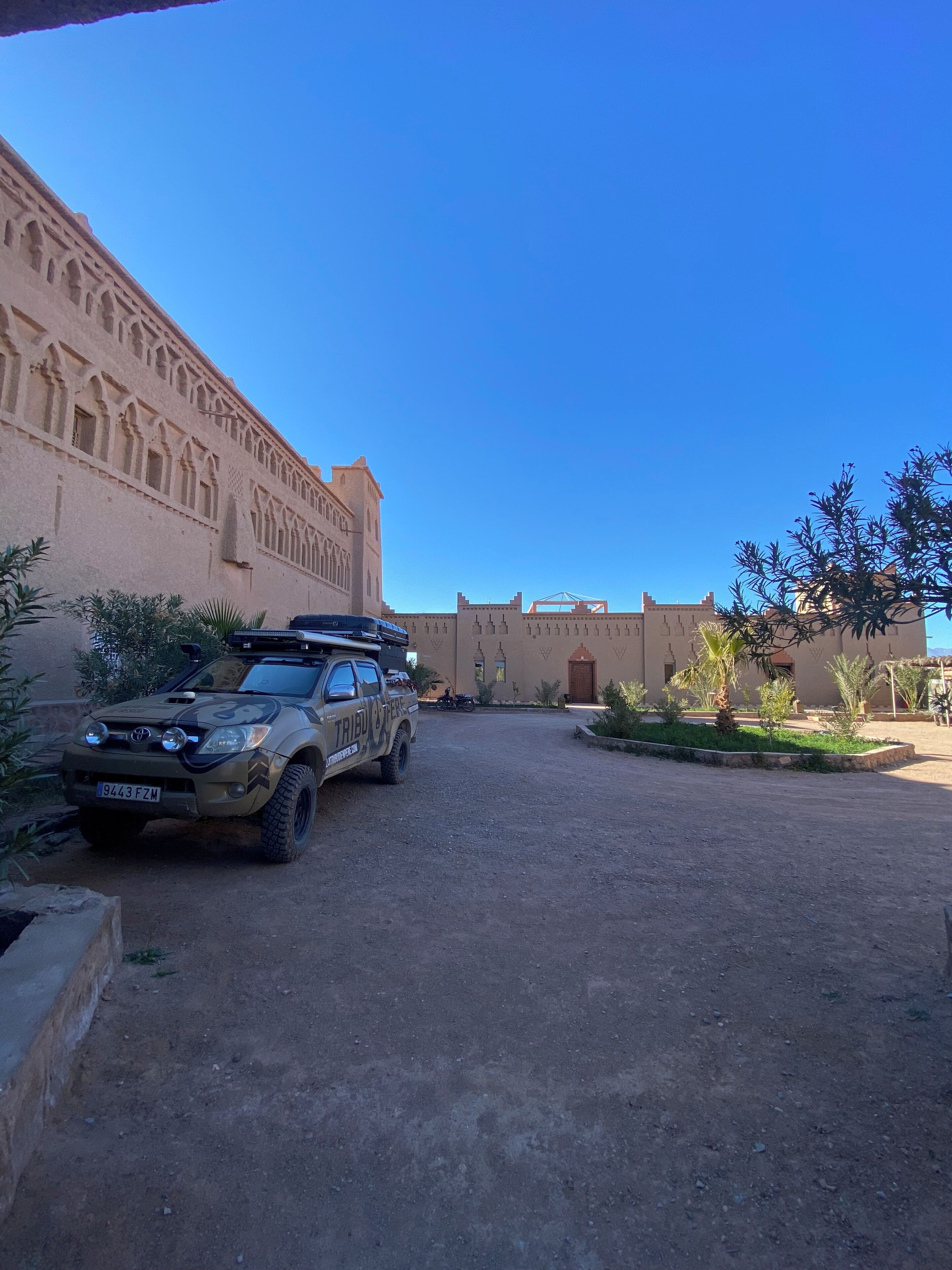 A desert-style building with a paved driveway and a parked off-road vehicle.