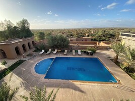 Zona de piscina con sillones de descanso y vistas del paisaje circundante.