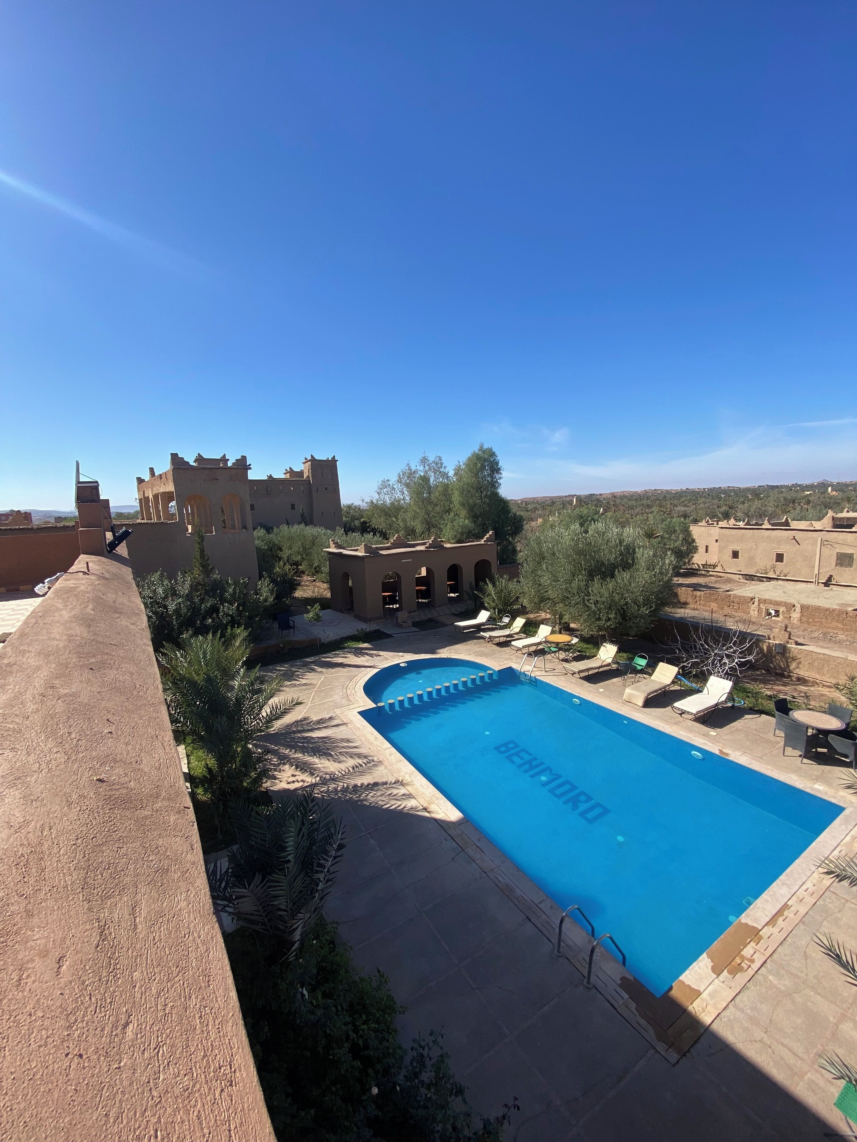 Zona de piscina amb gandules i un cel blau clar.