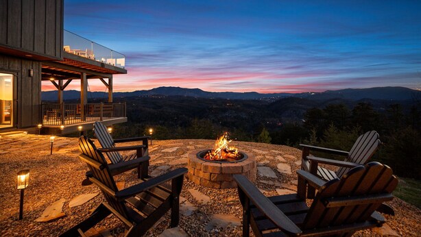 A fire pit with chairs and a deck overlooking a mountainous landscape at dusk. - VIEWS, VIEWS & more VIEWS! (Sevierville)
