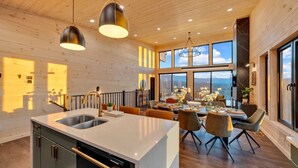 A modern kitchen with a central island, a dining area with a view, and wooden walls. - VIEWS, VIEWS & more VIEWS! (Sevierville)