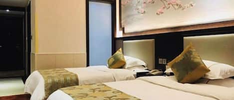 A hotel room with two beds, a painting of cherry blossoms, and a door to a hallway.