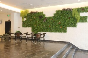 Eine Lobby mit grüner Wand, einer Treppe und Korbsesseln.