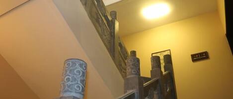 Una escalera con barandillas ornamentales y una lámpara colgante.