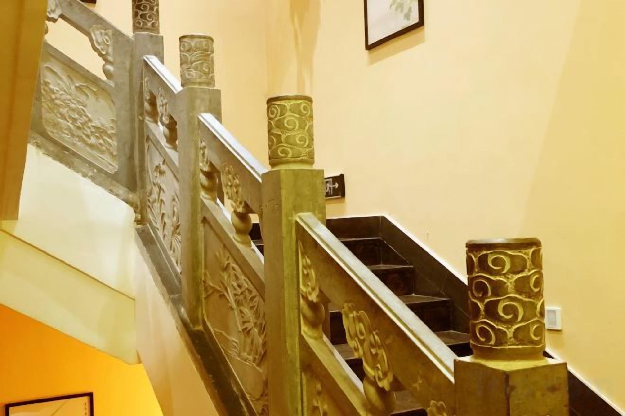 Un escalier orné de balustrades travaillées et un vase décoratif sur la plateforme.