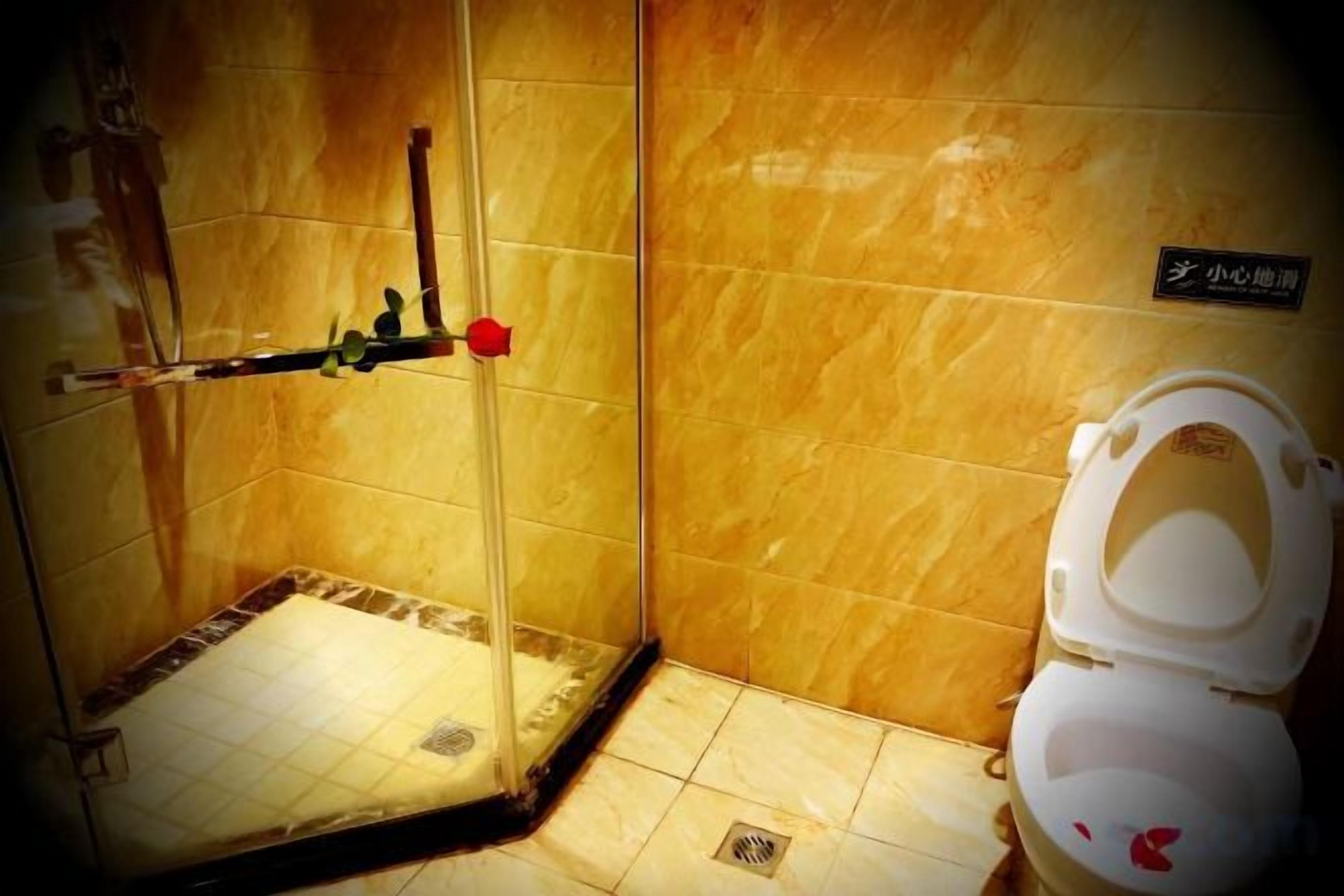 A bathroom with a shower, toilet, and a sign on the wall.