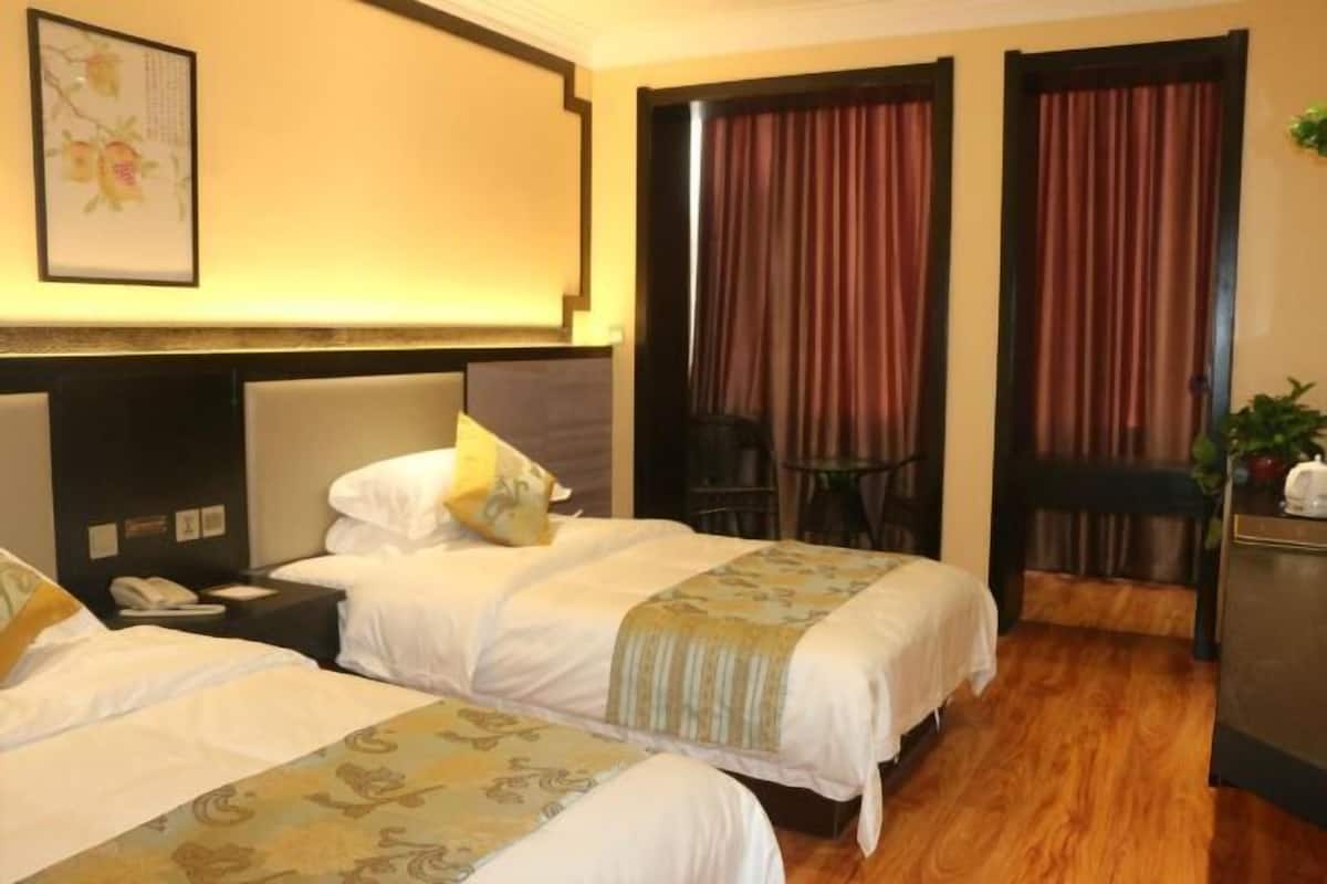 Hotellihuone, jossa on kaksi sänkyä, työpöytä, tuoli ja ovi, jossa on verhot.