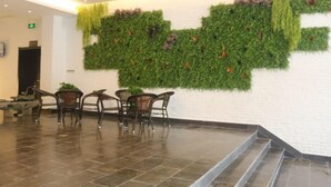 A lobby with a green wall, a reception desk, and a seating area with chairs. - Huaxia Jingdu Business Hotel (Taiyuan)
