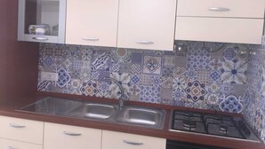 A kitchen with white cabinets, a double sink, and a gas stove. - On the Chiaia Beach in Procida the intriguing "Whisper of the Mimant." (Procida)