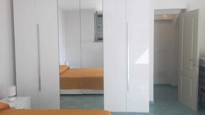 A bedroom with a bed, wardrobe, and a small window. - On the Chiaia Beach in Procida the intriguing "Whisper of the Mimant." (Procida)