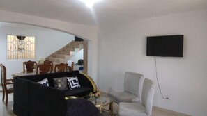 Un soggiorno con divano, poltrona e televisore piatto montato a parete.