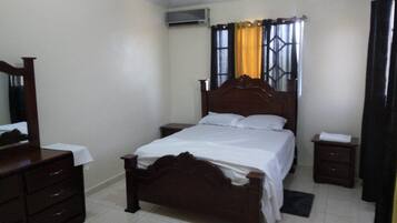 A bedroom with a wooden bed, a nightstand, a dresser, and a mirror.