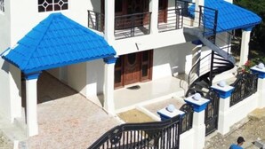 A two-story building with a blue roof, a balcony, and a staircase.