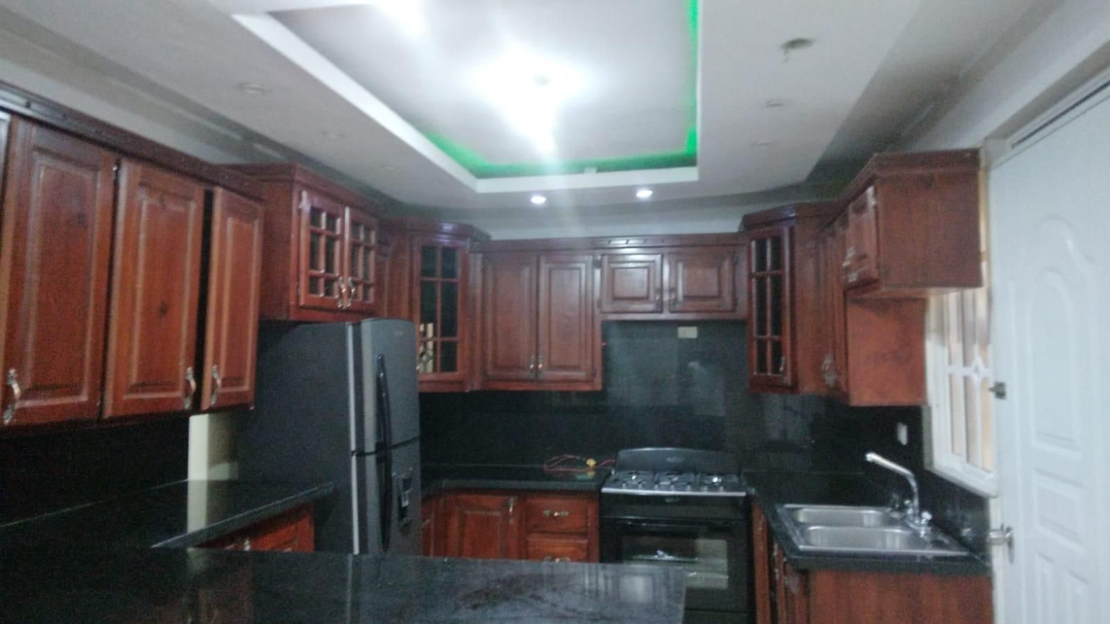 A kitchen with wooden cabinets, a refrigerator, a stove, and a sink.